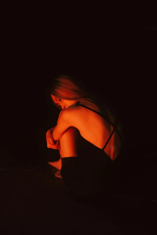 a woman sitting on the ground in the dark, pexels, petra collins, shy looking down, digital image, back - lit