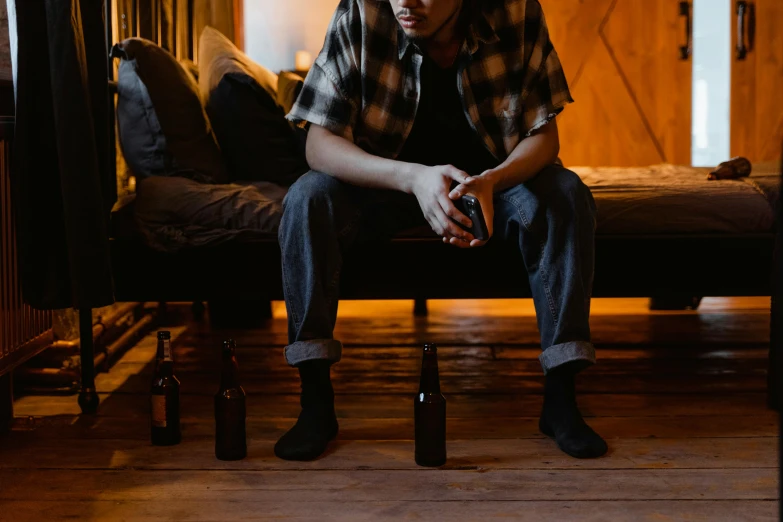 a man sitting on a bed in a room, by Carey Morris, trending on pexels, holding beer bottles, at the sitting couch, sad ambience, profile image