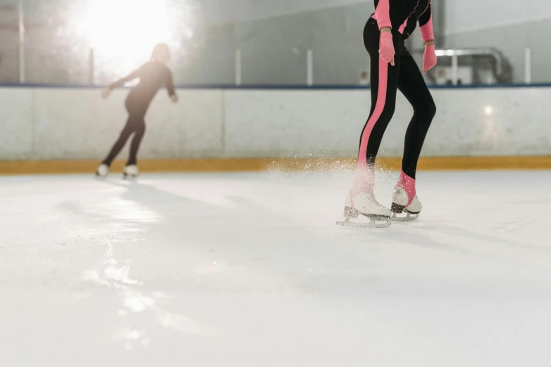 two people are skating on an ice rink, a picture, by Niko Henrichon, shutterstock, aerodynamic, skintight suits, indoor shot, pink