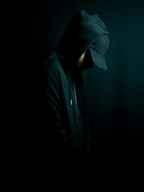 a man in a hoodie standing in the dark, an album cover, unsplash, dark hat, sullen, faceless people, cyber noir
