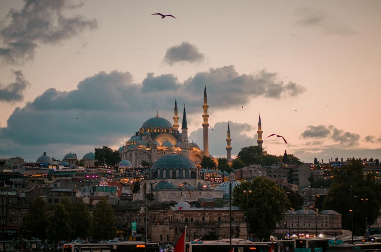 a large building sitting on top of a lush green hillside, a colorized photo, by Ismail Acar, pexels contest winner, hurufiyya, with great domes and arches, vista of a city at sunset, turqouise, gray