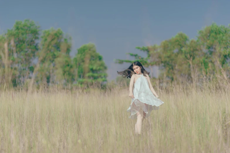 a woman walking through a field of tall grass, inspired by Oleg Oprisco, unsplash, portrait image, a young asian woman, porcelain skin ”