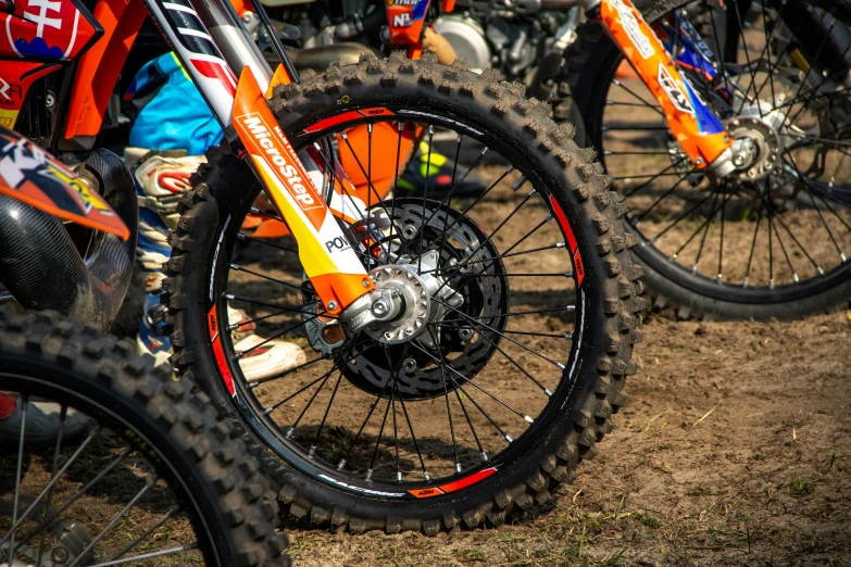 a group of dirt bikes parked next to each other, orange details, cogs and wheels, at racer track, avatar image