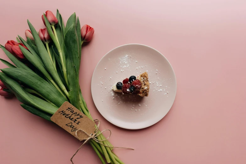 a white plate topped with a piece of cake next to a bunch of red tulips, pexels contest winner, made of flowers and berries, minimal pink palette, thumbnail, cardboard