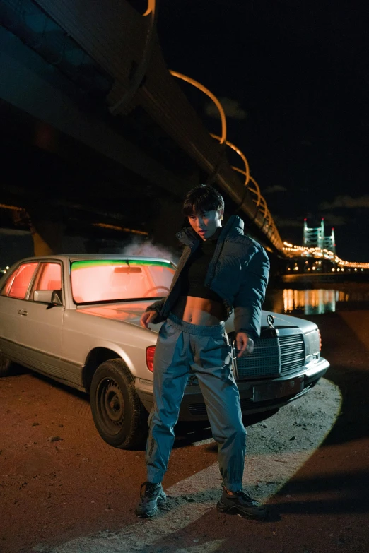 a man standing on the side of a road next to a car, an album cover, inspired by Elsa Bleda, trending on pexels, 8 0 s asian neon movie still, model posing, gta in moscow, river in front of him