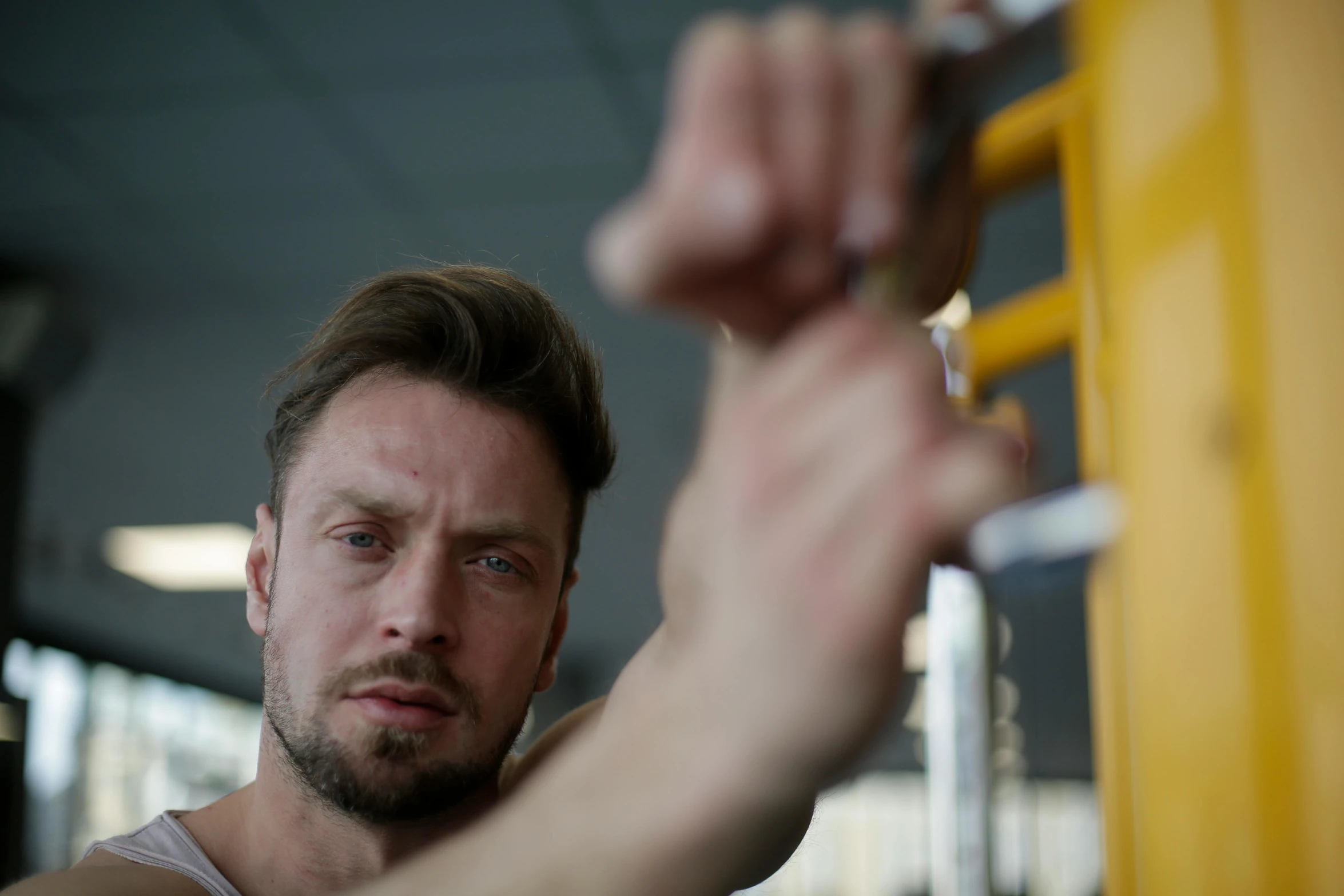 a man working out on a machine in a gym, a portrait, by Adam Marczyński, pexels contest winner, square masculine jaw, background image, sad look, cinematic shot ar 9:16 -n 6 -g