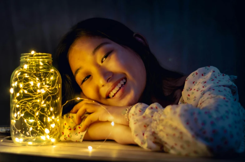 a young girl smiles next to a jar of fairy lights, pexels contest winner, light and space, louise zhang, teenage girl, soft backlighting, environmental shot