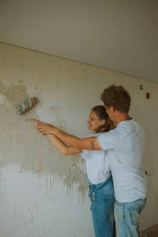 a man and a woman painting a wall, inspired by Elsa Bleda, pexels contest winner, arbeitsrat für kunst, low quality footage, dull flaking paint, sand - colored walls, summertime