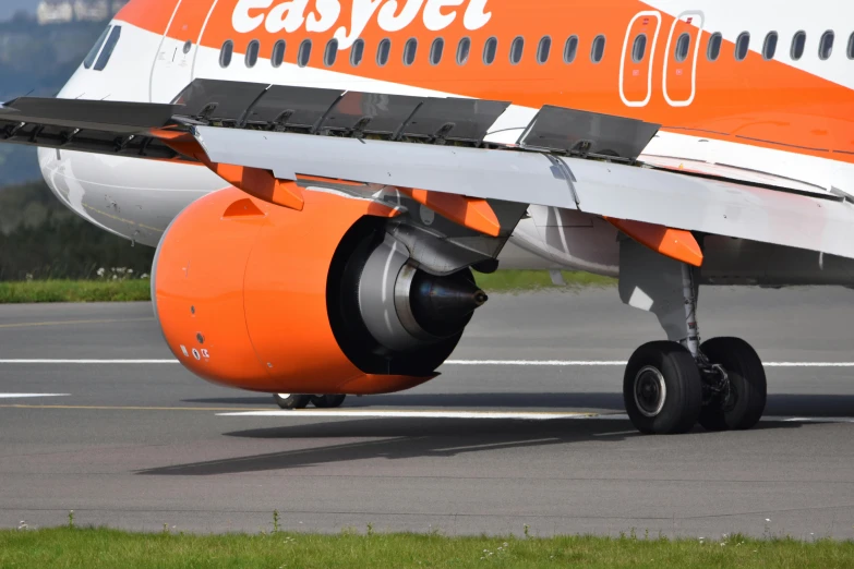 a large jetliner sitting on top of an airport runway, by Paul Bird, pexels contest winner, vibrant orange, edinburgh, bottom body close up, 15081959 21121991 01012000 4k