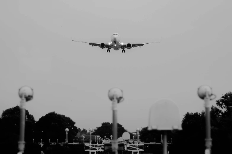 a black and white photo of an airplane coming in for a landing, a black and white photo, pexels contest winner, terminals, landing lights, hd footage, a green