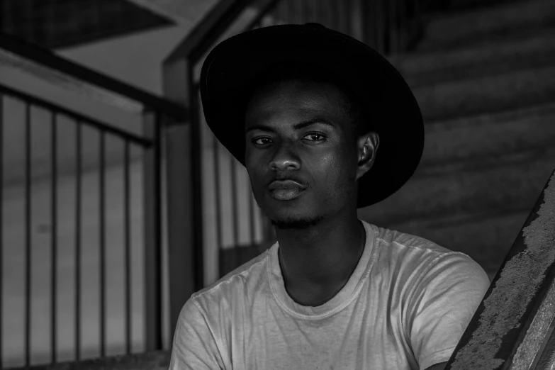 a black and white photo of a man wearing a hat, by Daniel Gelon, pexels contest winner, realism, brown skinned, casual pose, around 1 9 years old, david uzochukwu