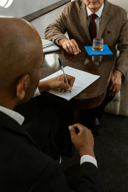 two men sitting at a table talking to each other, by Matt Cavotta, resignation, writing on a clipboard, thumbnail, high quality image