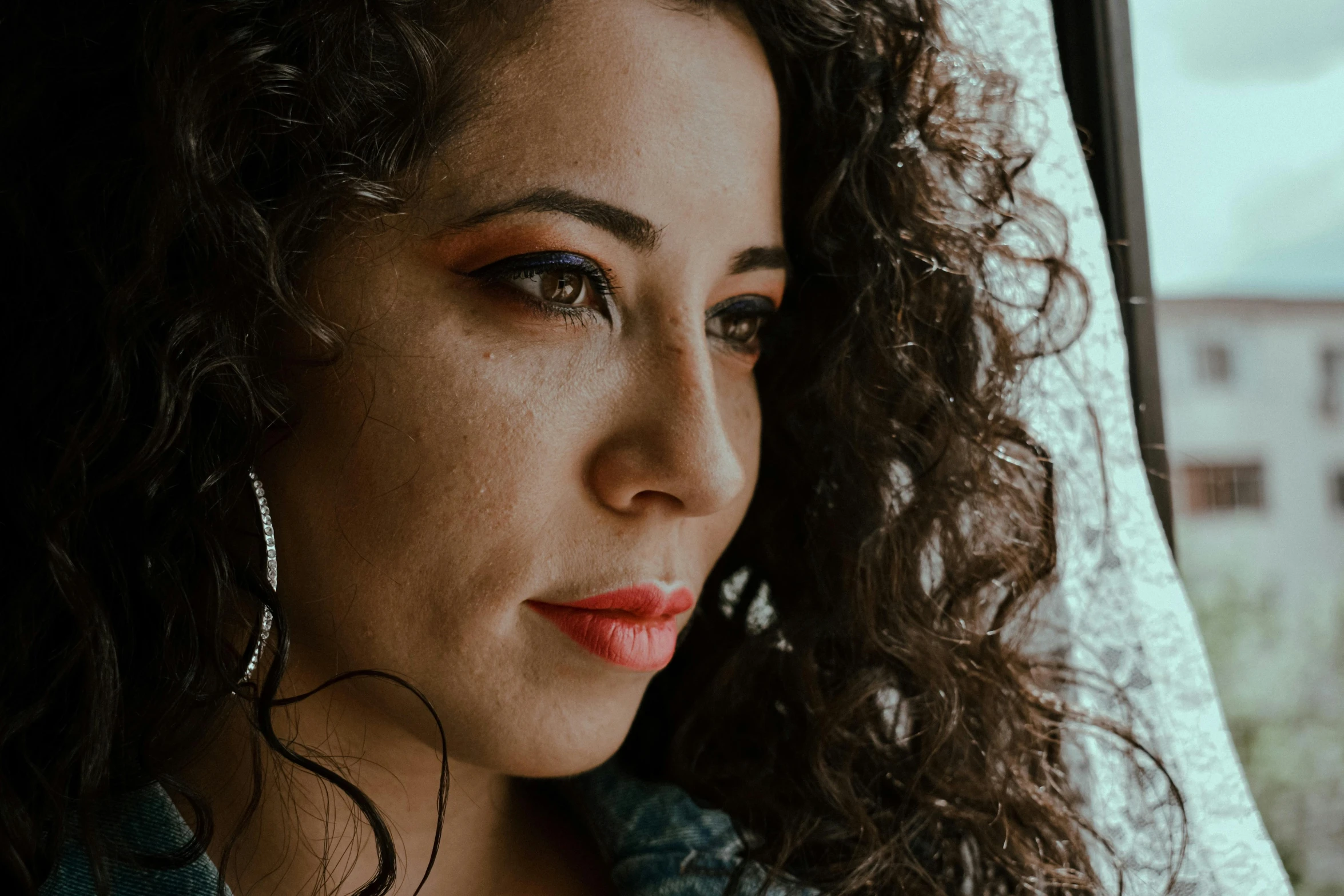 a woman with curly hair looking out a window, trending on pexels, fantastic realism, middle eastern skin, selena quintanilla perez, high angle closeup portrait, cinematic shot ar 9:16 -n 6 -g