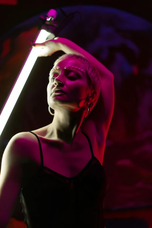 a woman in a black dress holding a neon light, pexels contest winner, light and space, chrome dance pole, profile image, doja cat, red glowing skin