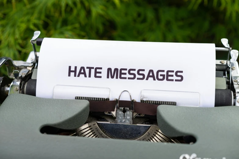 a typewriter with a paper that says hate messages, a cartoon, unsplash, outdoor photo, ad image, white, 1 2 9 7