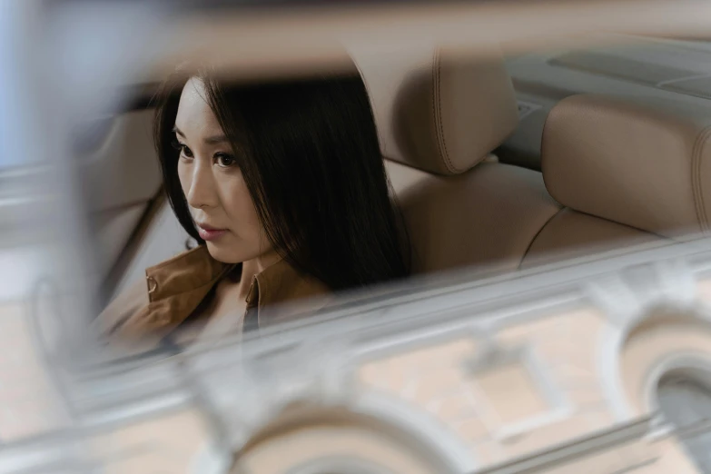 a woman sitting in the back seat of a car, an album cover, inspired by Zhu Da, pexels contest winner, pininfarina, mariko mori, serious focussed look, official vuitton editorial