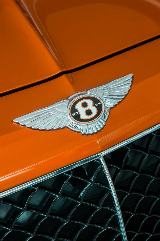 an orange bentley badge on the front of a car, pexels contest winner, each having six wings, studio quality, 8 k - n 9, bay area