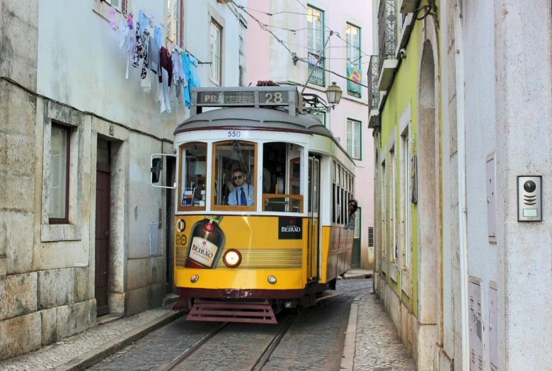 a yellow trolley traveling down a narrow street, inspired by Almada Negreiros, pexels contest winner, art nouveau, square, brown, gray men, brazilian ronaldo