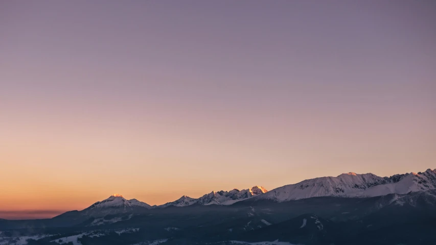 a couple of people riding skis on top of a snow covered slope, pexels contest winner, minimalism, sunset panorama, distant mountains lights photo, photography of kurzgesagt, earth and pastel colors