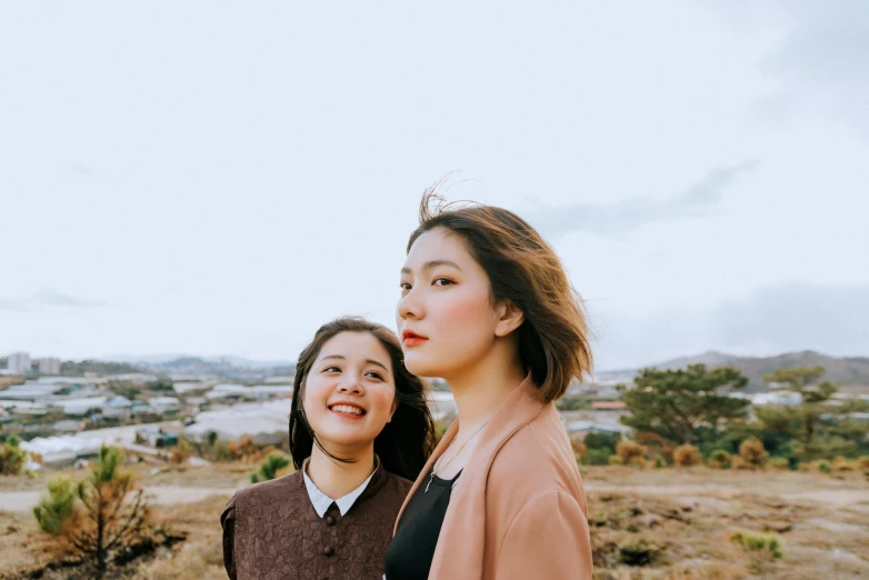 a couple of women standing next to each other, inspired by Kim Jeong-hui, pexels contest winner, hills in the background, youthful appeal, hana alisa omer, brown