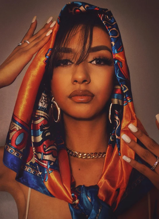 a close up of a person wearing a scarf, an album cover, trending on pexels, rapper jewelry, arabian beauty, pretty pretty face, orange and blue tones