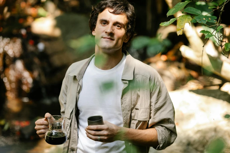 a man standing in a forest holding a cup of coffee, maxwell boas, avatar image, aussie baristas, riccardo scamarcio