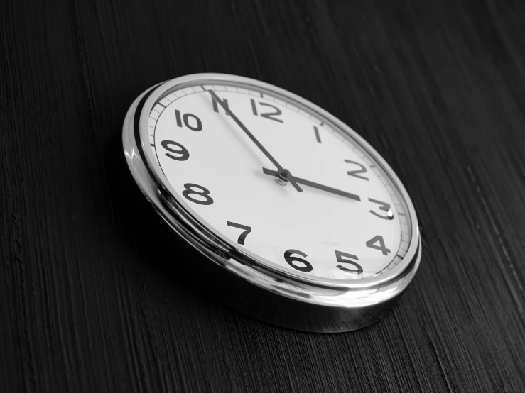 a clock sitting on top of a wooden table, back and white, profile image, digital image, item
