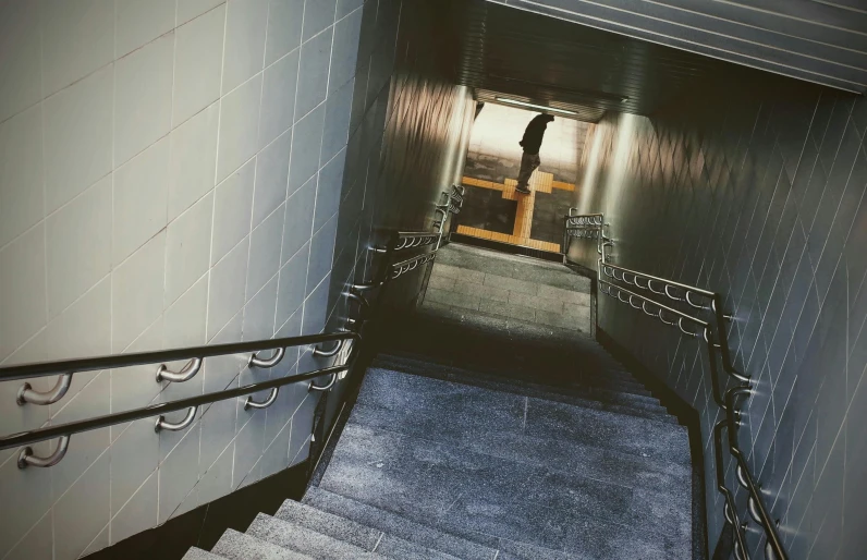 a man riding a skateboard down a flight of stairs, an album cover, inspired by Elsa Bleda, unsplash, brutalism, entrance to a dark tunnel, ignant, indoor picture, lomo photograph