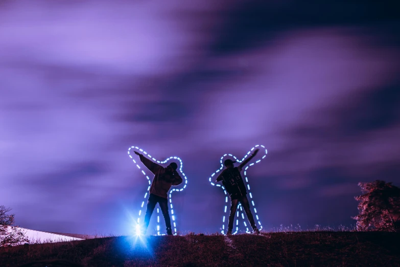 a couple of people that are standing in the grass, a hologram, inspired by Storm Thorgerson, pexels contest winner, interactive art, blue lights and purple lights, standing on a hill, string lights, triumphant pose