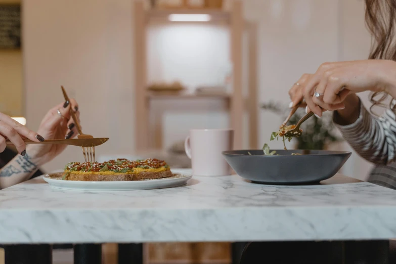 a couple of women sitting at a table with plates of food, pexels contest winner, process art, background image, blurry image, about to consume you, ☕ on the table