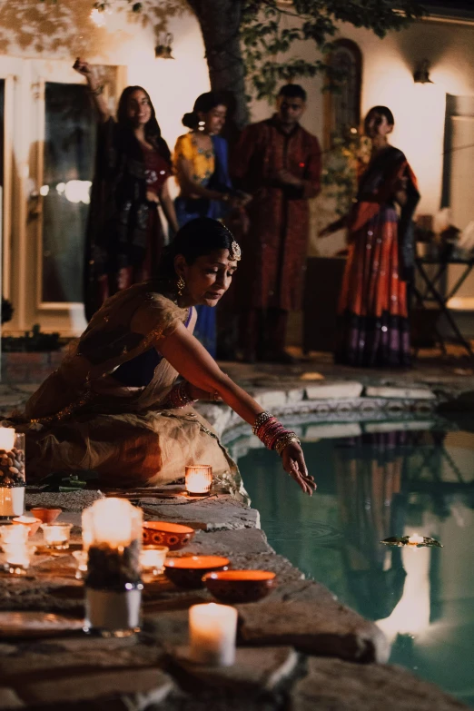 a group of people standing around a pool, an album cover, pexels contest winner, renaissance, hindu aesthetic, candle lighting, performance, adi meyers