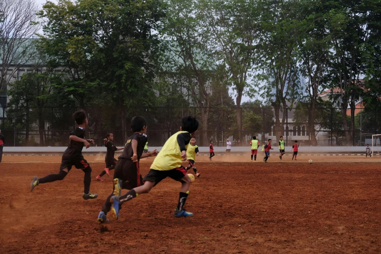 a group of young men playing a game of soccer, by Basuki Abdullah, pexels contest winner, panorama shot, ocher, kids playing, shot on iphone 6