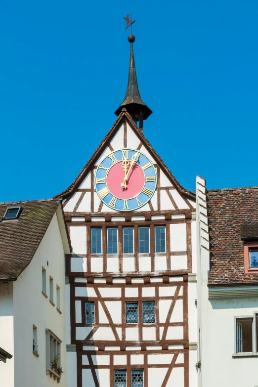 a building with a clock on the side of it, rossier, tudor architecture, white buildings with red roofs, sky blue