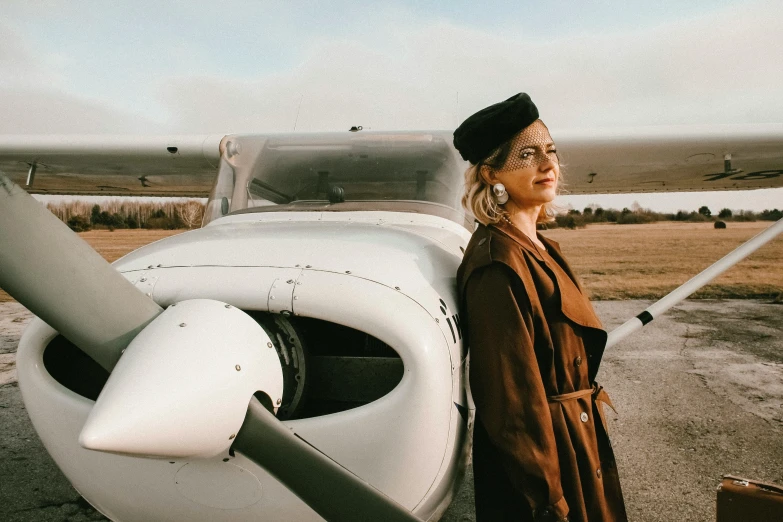 a woman standing in front of an airplane, a portrait, by Emma Andijewska, pexels contest winner, dressed like in the 1940s, cessna glider plane, thumbnail, fall season
