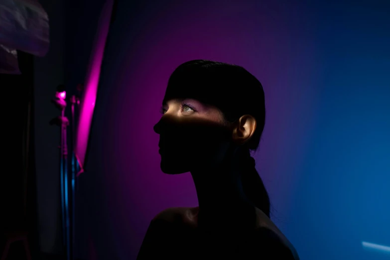 a close up of a person in a dark room, an album cover, pexels contest winner, light and space, blue and pink lighting, on a mannequin. studio lighting, looking to the side, coloured gel studio light