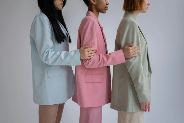 a group of three women standing next to each other, trending on pexels, aestheticism, wearing a colorful men's suit, pale colors, faceless people, pearlescent