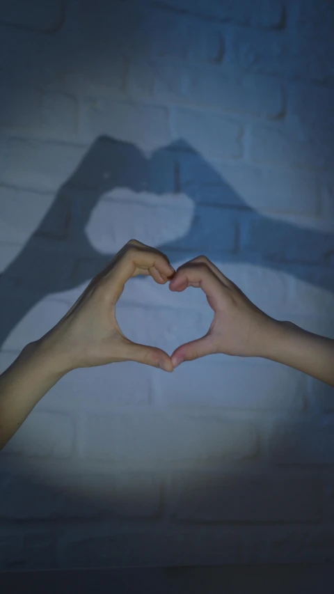 a person making a heart shape with their hands, pexels, dark blue, instagram post, soft shadow, shot on sony a 7