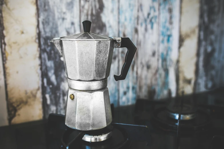a silver coffee pot sitting on top of a stove, inspired by Géza Dósa, pexels contest winner, old kitchen backdrop angled view, grey, italian, wooden