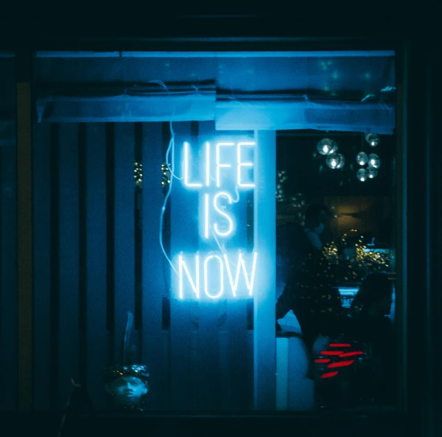 a neon sign that says life is now, a photo, inspired by Tracey Emin, unsplash contest winner, maximalism, cold blue light from the window, alessio albi, neon standup bar, profile image