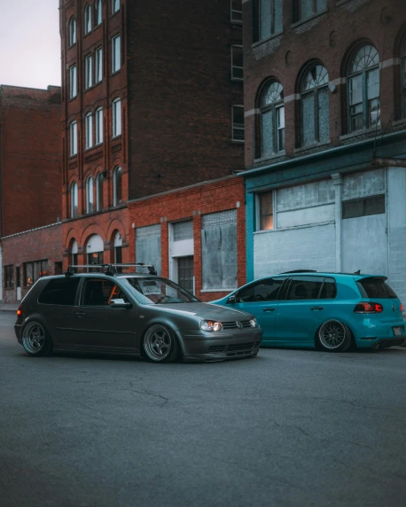 two cars parked next to each other on a city street, by Adam Rex, pexels contest winner, silver and cool colors, extreme shitty car mods, two different characters, low quality photo