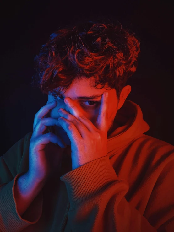 a man with curly hair talking on a cell phone, an album cover, inspired by Elsa Bleda, trending on pexels, portrait of depressed teen, red colored, facepalm, bisexual lighting