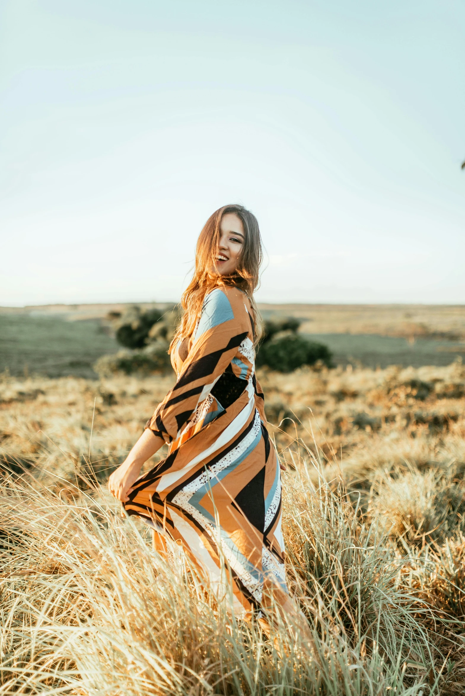 a woman standing in the middle of a field, unsplash, visual art, wearing desert poncho, at a fashion shoot, stripes, sarong