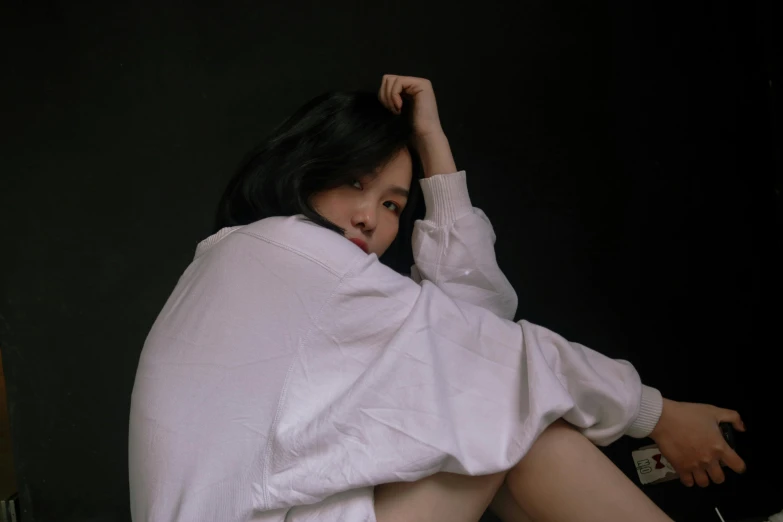 a woman sitting on top of a bed covered in a blanket, dressed in a white t shirt, korean idol, with a black background, trending photo