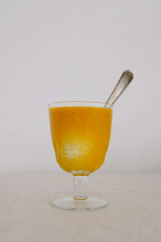 a glass of orange juice with a spoon in it, renaissance, medium-shot, on display, ignant, mango