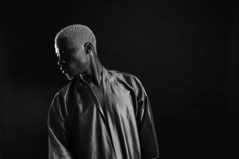 a man standing in front of a black background, an album cover, by Barthélemy Menn, pexels contest winner, in a silver silk robe, kousuke oono, thinker, black main color