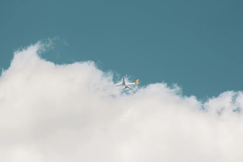 a large jetliner flying through a cloudy blue sky, a picture, pexels contest winner, minimalism, sitting in a fluffy cloud, yellow clouds, thumbnail, 8
