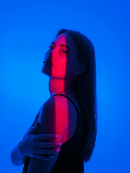 a woman standing in front of a blue background, red and blue back light, profile image, !!! colored photography, instagram post