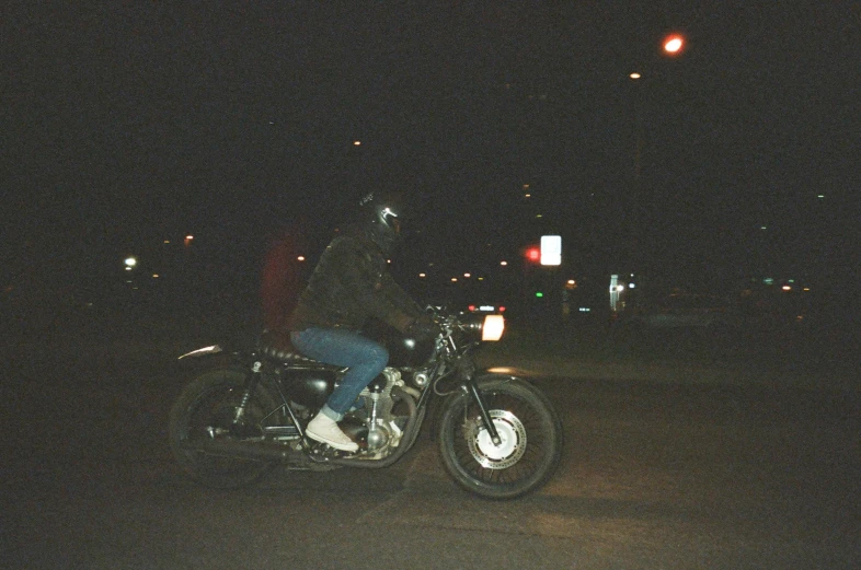 a man riding on the back of a motorcycle at night, an album cover, unsplash, photorealism, grainy film photo, disposable camera photo, streetwear, grainy movie still