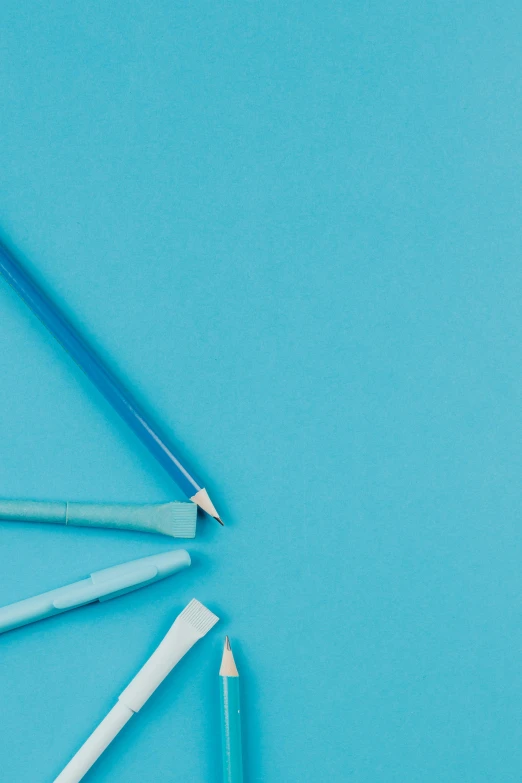 a group of pencils sitting on top of a blue surface, 9 9 designs, thumbnail, surgical supplies, papers