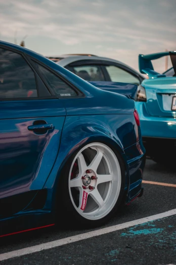 two cars parked next to each other in a parking lot, a picture, by Matt Cavotta, unsplash, high detailed wheels, blue themed, wide body, festivals